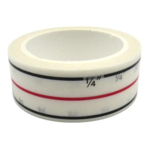 May include: A roll of white washi tape with black and red stripes and markings that include the fraction "1/4".
