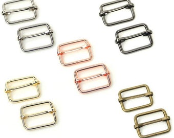 Op de afbeelding: Set van tien metalen schuifgespen in vier verschillende afwerkingen: zilver, zwart, rosé goud en antiek messing. Elke gesp is rechthoekig met een gladde, afgeronde rand.