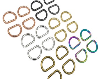 May include: Assortment of metal D-rings in various colors, including black, gold, silver, rose gold, and rainbow. The D-rings are arranged in rows, with the largest rings at the top and the smallest rings at the bottom.  EMMALINE HARDWARE is printed at the bottom of the image.