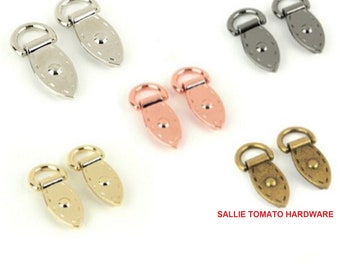 May include: Set of six metal D-ring strap loops in four different finishes: silver, gold, rose gold, and antique brass. Each loop has a decorative oval shape with a small stud in the centre.