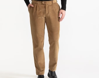 May include: A man wearing a black turtleneck sweater and brown corduroy pants. He is wearing black shoes.