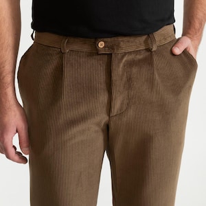 Puede incluir: Pantal&oacute;n de pana marr&oacute;n con un frente plisado y un cierre de bot&oacute;n. El pantal&oacute;n tiene un ajuste delgado y una pierna recta.