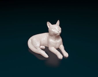 Op de afbeelding: Een wit keramiek beeldje van een liggende kat met zijn kop naar de zijkant gedraaid. De kat heeft een realistisch uiterlijk met vachtdetails.