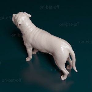 May include: A white, 3D printed dog figurine, viewed from above, with its tail curled to the side. The figurine is posed as if the dog is standing and looking to the left.