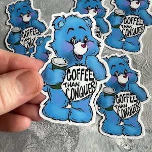 以下が含まれることがあります： コーヒーカップと「Coffee Than Conquer」というテキストが書かれた青い漫画のクマのステッカーが5枚です。