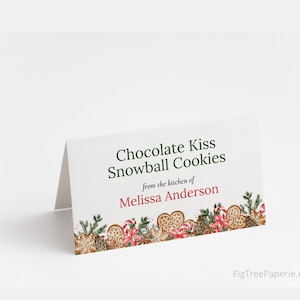 May include: A white card with green text that reads "Chocolate Kiss Snowball Cookies from the kitchen of Melissa Anderson". The card has a border of red and green Christmas-themed illustrations.