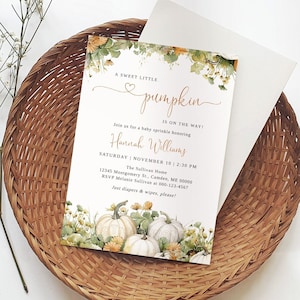 Puede incluir: Una invitación a un baby shower con una ilustración de acuarela de calabazas y follaje de otoño. La invitación dice "A Sweet Little Pumpkin is on the Way!" e incluye el nombre "Hannah Williams", la fecha y hora del baby shower, y la ubicación. La invitación también solicita a los invitados que traigan pañales y toallitas.