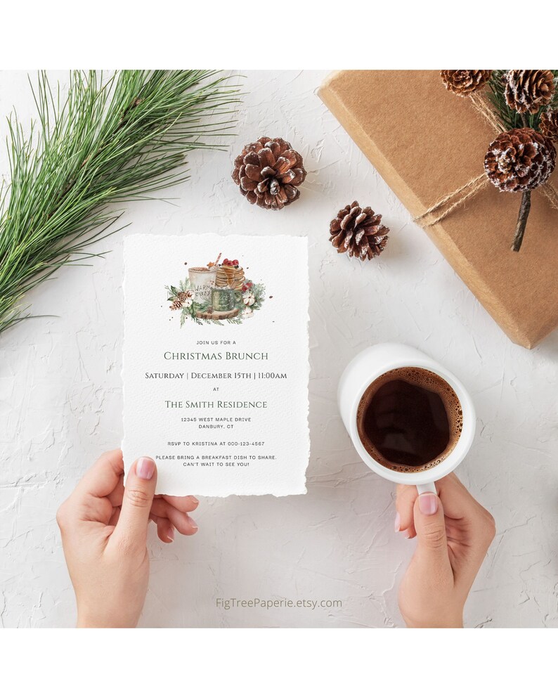 May include: A Christmas brunch invitation with a watercolor illustration of a mug of hot cocoa with marshmallows and a plate of pancakes. The invitation includes the date, time, and location of the event. RSVP information is also included.