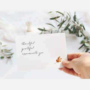 May include: A white card with the handwritten text "thankful grateful appreciate you" and a pressed, dried, orange leaf.