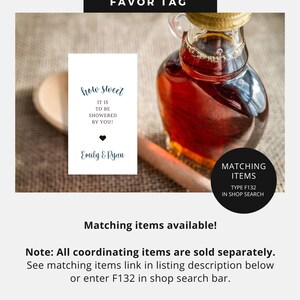 May include: A favour tag with the text "how sweet it is to be showered by you!" and "Emily & Ryan". The tag is next to a bottle of maple syrup and a wooden spoon. The tag is white with blue text. The text "Matching Items Type F132 in Shop Search" is on a black circle.