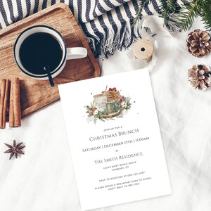 May include: A white invitation card with green and brown watercolor illustrations of a coffee cup, a plate of pancakes, and a sprig of holly. The text on the card reads "Join us for a Christmas Brunch, Saturday | December 15th | 11:00 AM, at The Smith Residence, 12345 West Maple Drive, Danbury, CT, RSVP to Kristina at 000-123-4567, Please bring a breakfast dish to share. Can't wait to see you!"