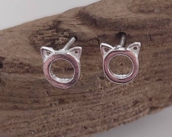 May include: A pair of silver cat face stud earrings. The earrings are small and delicate, with a simple design.