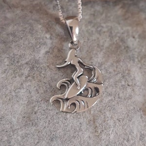 Puede incluir: Colgante de plata con dise&ntilde;o de surfista. El colgante muestra un surfista sobre una tabla, surfeando una ola. La cadena es fina y el acabado pulido. Un accesorio cl&aacute;sico con tem&aacute;tica de surf.