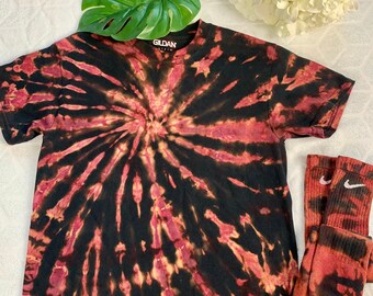 May include: A black and red tie-dye t-shirt with the Gildan logo on the front. The shirt is paired with a pair of red and black tie-dye socks.