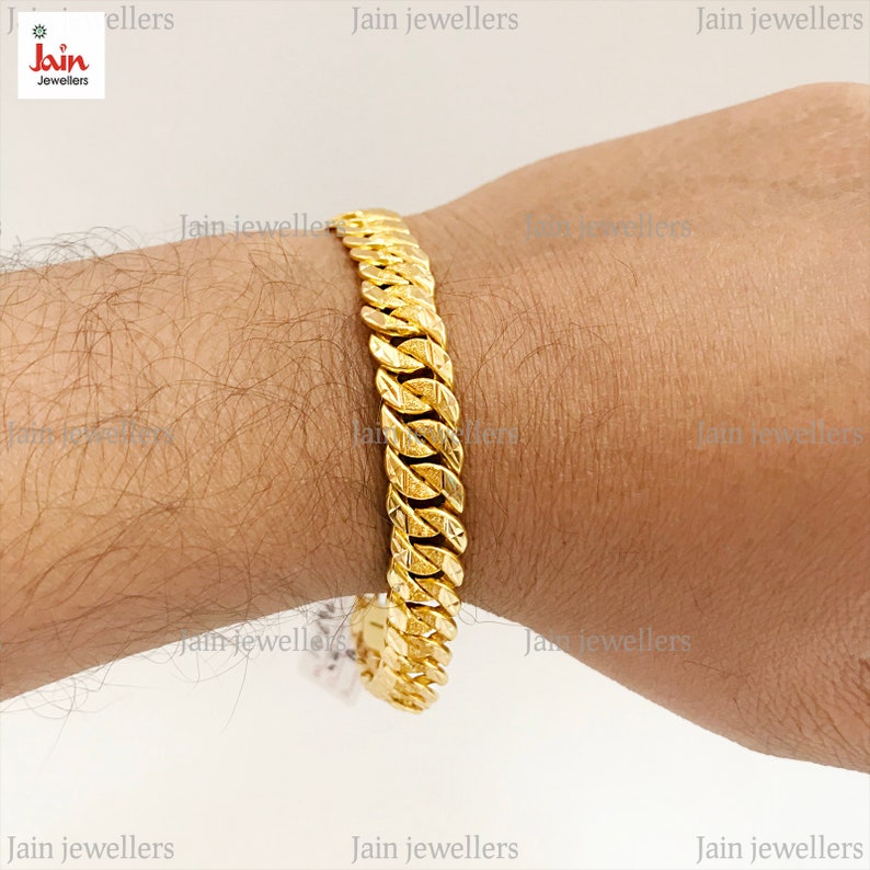 May include: A gold chain bracelet with a textured design. The bracelet is on a person's wrist.