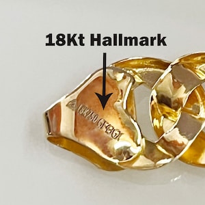 May include: Close-up of a gold chain bracelet with a 18Kt hallmark stamped on a link. The chain is made of thick, interlocking links.