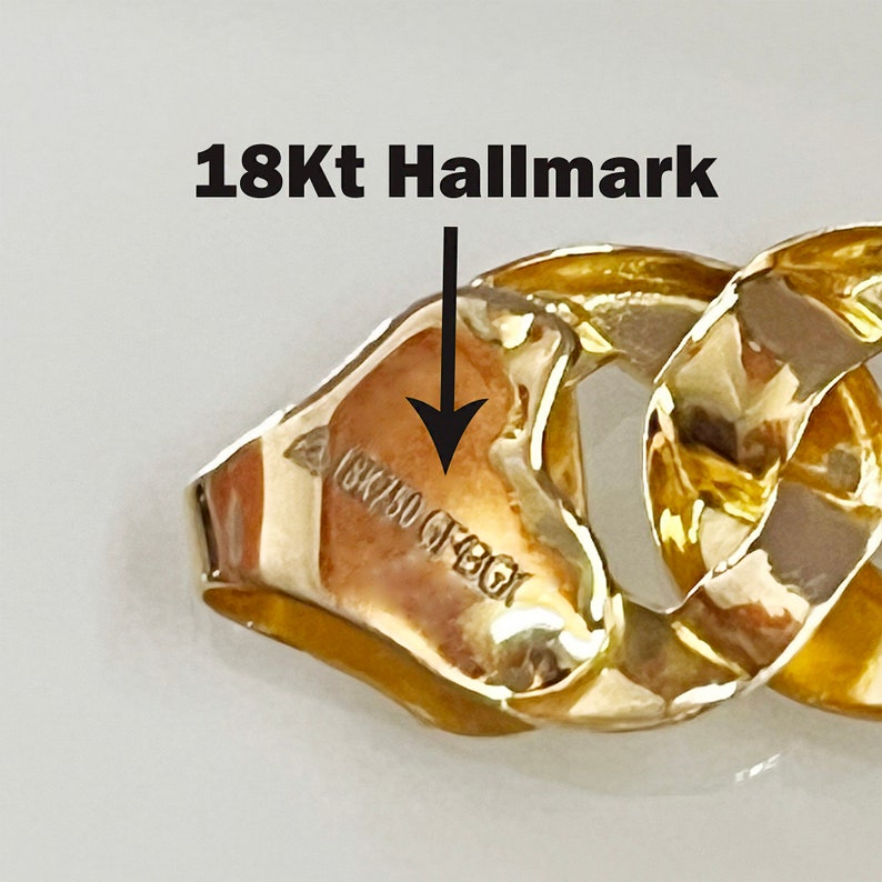 May include: Close-up of a gold chain bracelet with a 18Kt hallmark stamped on a link. The chain is made of thick, interlocking links.