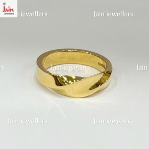 Puede incluir: Un anillo dorado con un dise&ntilde;o retorcido. El anillo tiene una superficie pulida y un aspecto moderno. El anillo es una joya.