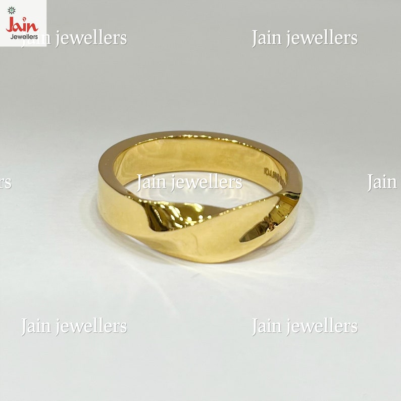 Puede incluir: Un anillo dorado con un dise&ntilde;o retorcido. El anillo tiene una superficie pulida y un aspecto moderno. El anillo es una joya.