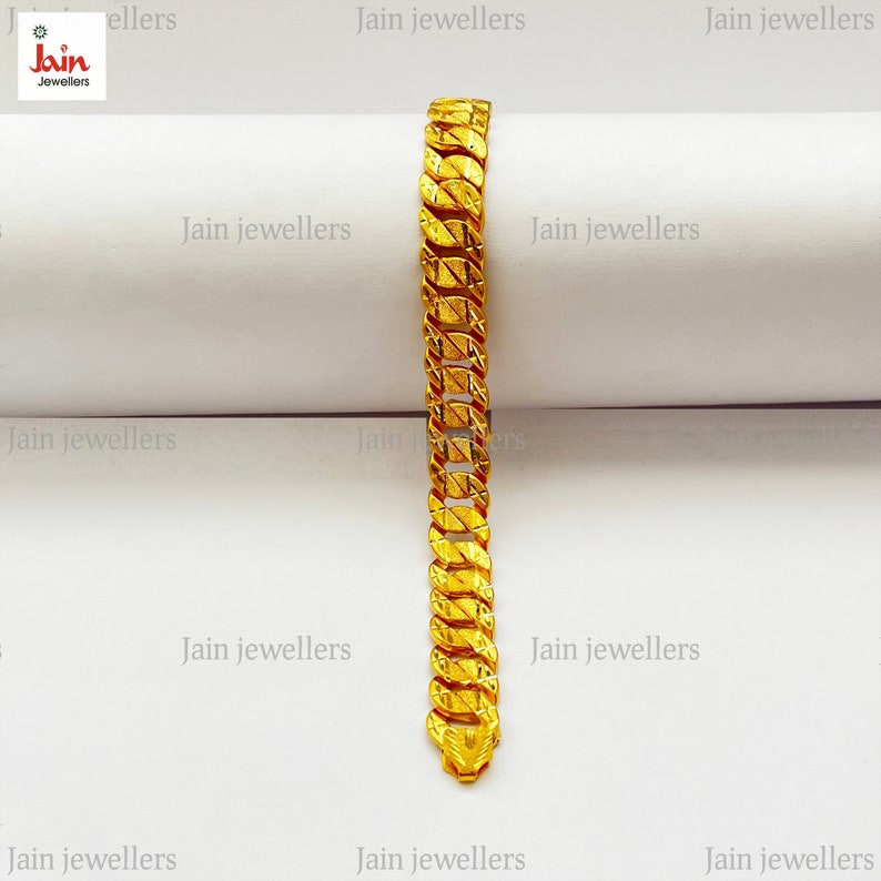 May include: A gold chain bracelet with a textured design. The bracelet is on a white surface with the text "Jain Jewellers" repeated multiple times.