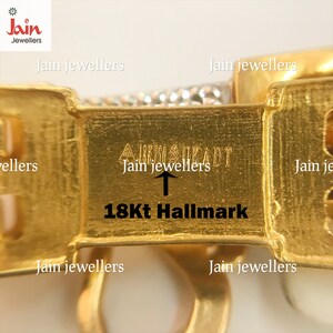 May include: Close-up of a gold bracelet with a 18Kt Hallmark and the inscription "Jain Jewellers" on the clasp.