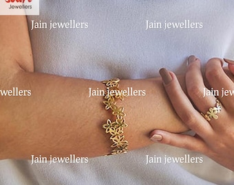 May include: A gold bracelet with a delicate floral design. The bracelet is on a person's wrist. The text "Jain Jewellers" appears multiple times in the image.