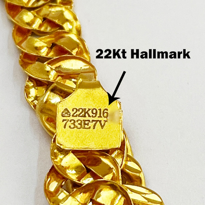 May include: A gold chain necklace with a 22Kt hallmark. The hallmark is stamped on a small tag attached to the chain. The tag reads "22K916 733E7V".
