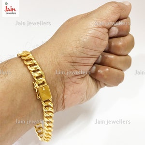 May include: A gold chain bracelet with a clasp closure. The bracelet is on a person's wrist.