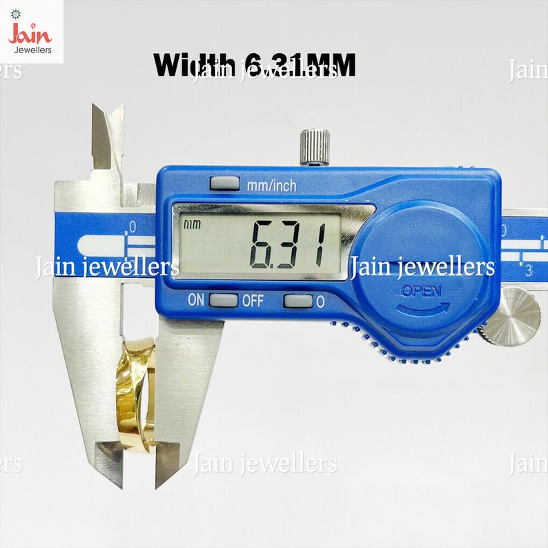 Puede incluir: Un calibrador digital mide un anillo dorado. La pantalla digital muestra un ancho de 6,31 mm. El calibrador es azul con texto blanco, y la imagen incluye el texto "Jain jewellers".