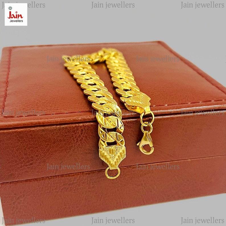 May include: A gold chain bracelet with a textured design. The bracelet is in a brown leather box with the text "Jain Jewellers" printed on the box.