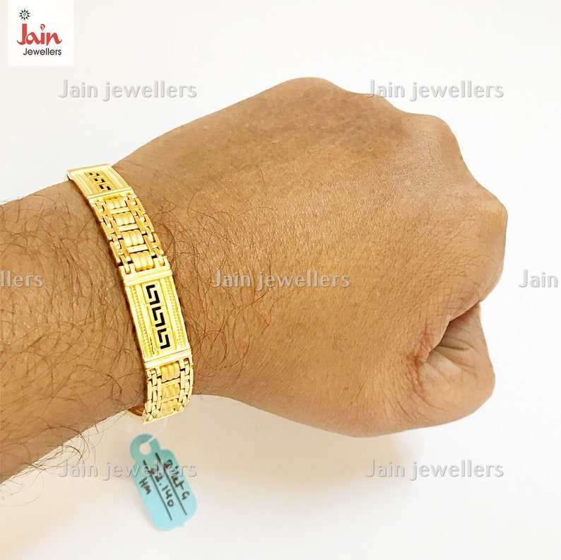 Puede incluir: Un brazalete de oro con un dise&ntilde;o geom&eacute;trico. El brazalete est&aacute; en la mu&ntilde;eca de una persona.