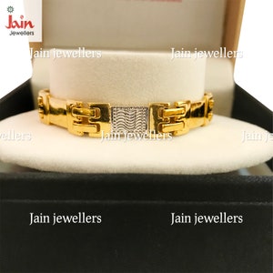 May include: A gold bracelet with a textured design. The bracelet is in a black box with the words "Jain Jewellers" printed on it.