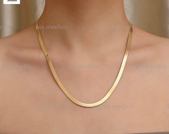 May include: A gold-colored snake chain necklace. The chain is made of a thin, flat metal and has a smooth, polished finish.
