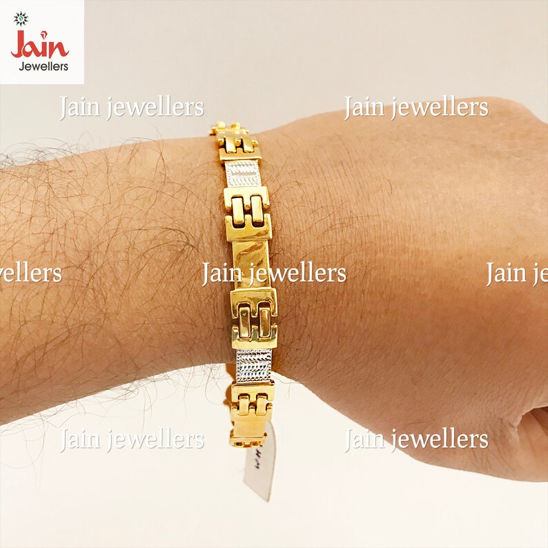 May include: A gold and silver bracelet with a square link design. The bracelet is on a person's wrist.