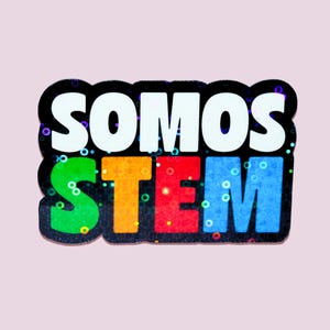 Może przedstawiać: Kolorowa naklejka z napisem "SOMOS STEM". Słowo "SOMOS" jest białe, nad słowem "STEM", które jest w kolorze zielonym, pomarańczowym, czerwonym i niebieskim. Projekt ma czarną obwódkę i brokat.