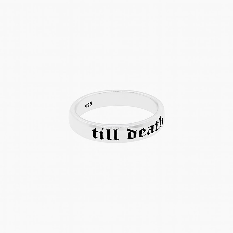 May include: A silver ring with the inscription "till death" in black gothic font. The ring is a simple band design with the number "925" visible. The ring is set against a white background.