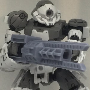 以下が含まれることがあります： 白とグレーのロボットのおもちゃで、大きなグレーの銃を持っています。ロボットは白い頭で、黒い目と黒い口をしています。