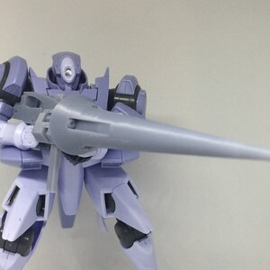 May include: A purple and gray robot action figure holding a long, gray spear-like weapon. The robot has a single, large eye on its head.