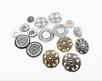 May include: Assortment of decorative buttons in various colors and patterns, including black and white, gold, and silver. The buttons feature intricate designs, such as floral motifs, geometric shapes, and swirls.