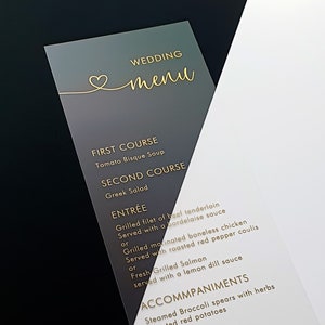 Menu weselne z przezroczystego akrylu z folią w kolorze złotym i sercem. Spersonalizowane, spersonalizowane menu z kaligrafią tekstową, wydrukowane różowo-złotą lub srebrną folią.