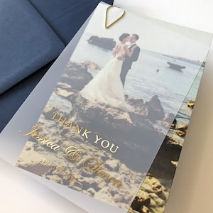 Cartão de agradecimento com impressão em folha de ouro em velino. Cartão de casamento em camadas, semitransparente, com aparência fosca e com fundo fotográfico dos noivos.