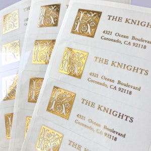 Könnte beinhalten: Goldfolien-Rückseitenaufkleber mit einem dekorativen Buchstaben K und dem Text "THE KNIGHTS" und "4321 Ocean Boulevard Coronado, CA 92118".