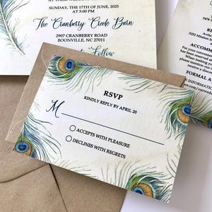 Könnte beinhalten: Hochzeitseinladungs-Set mit Pfauenfedermuster in Blau, Grün und Gold. Die RSVP-Karte bietet Optionen zum Akzeptieren oder Ablehnen. Die Einladung enthält Datum, Uhrzeit und Ort der Hochzeit.