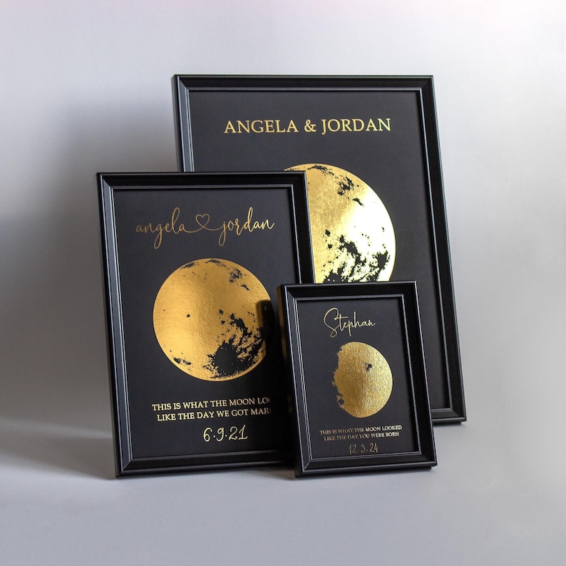 May include: Four framed prints with black frames and black backgrounds. The prints feature gold foil moon designs and text. The text includes names and dates, such as "Angela & Jordan" and "6.9.21".