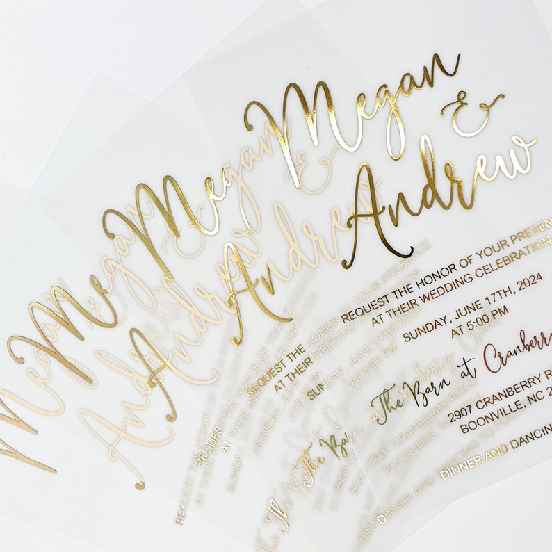 May include: A wedding invitation with gold foil lettering on a translucent paper background. The invitation reads "Megan & Andrew" and includes the date and time of the wedding, "Sunday, June 17th, 2024 at 5:00 PM" and the location, "The Barn at Cranberry, 2907 Cranberry Rd, Boonville, NC 27011".