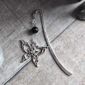 Könnte beinhalten: Silbernes Lesezeichen mit einem keltischen Knoten-Schmetterlingsdesign und einer schwarzen Perle. Der Schmetterling hat einen klaren Strassstein in der Mitte.