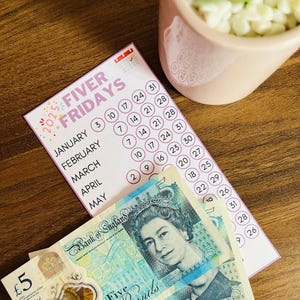 Pode incluir: Um calendário rosa e branco com o texto "2025 FIVER FRIDAYS" e uma lista de meses com datas circuladas. O calendário está sobre uma superfície de madeira com duas notas de cinco libras.