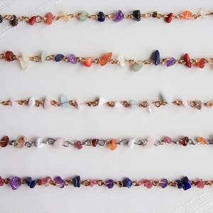 May include: Five copper chain bracelets with various colored gemstone beads. The bracelets feature a mix of pink, red, orange, yellow, green, blue, and purple beads.