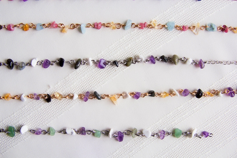 May include: Four strands of necklaces with various colored stones and metal chain links. The stones are small and appear to be natural.