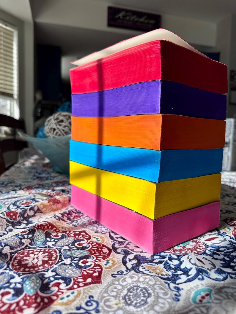 A complete 6-book set of Rina Kent's Legacy of Gods series featuring custom sprayed edges. The book edges are airbrushed in a solid rainbow gradient of red, purple, orange, blue, yellow, and pink to perfectly match the original covers. The books are stacked on a white shelf in a minimalist "BookTok" aesthetic style.